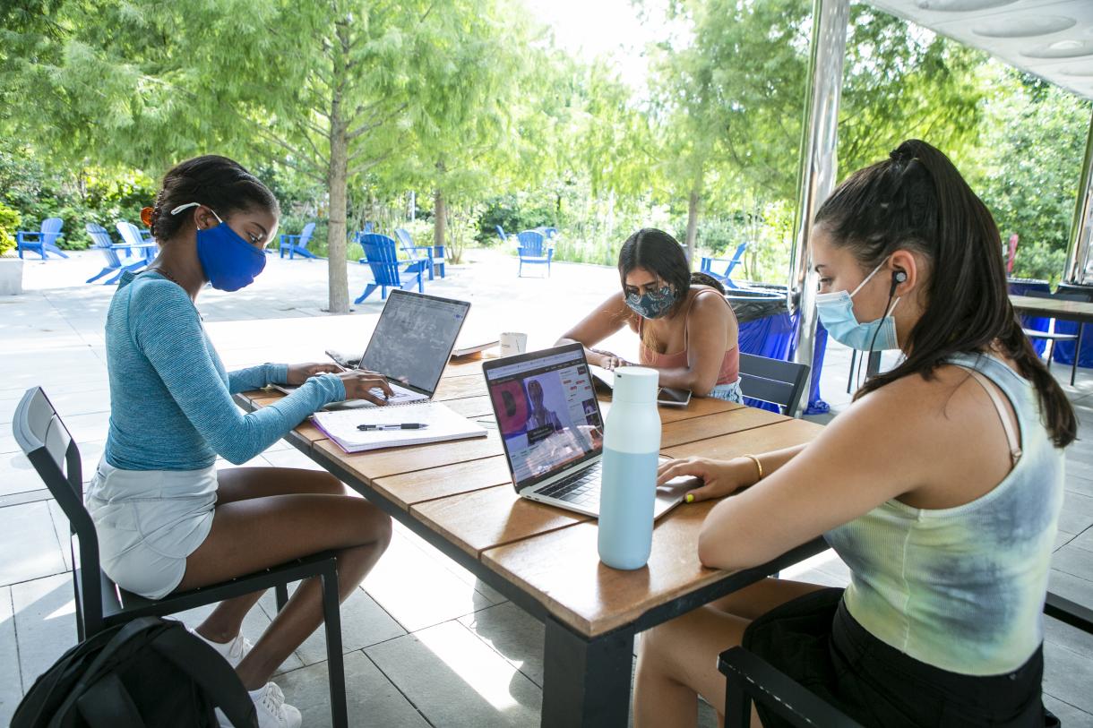 3 Duke students sitting outside working on laptops
